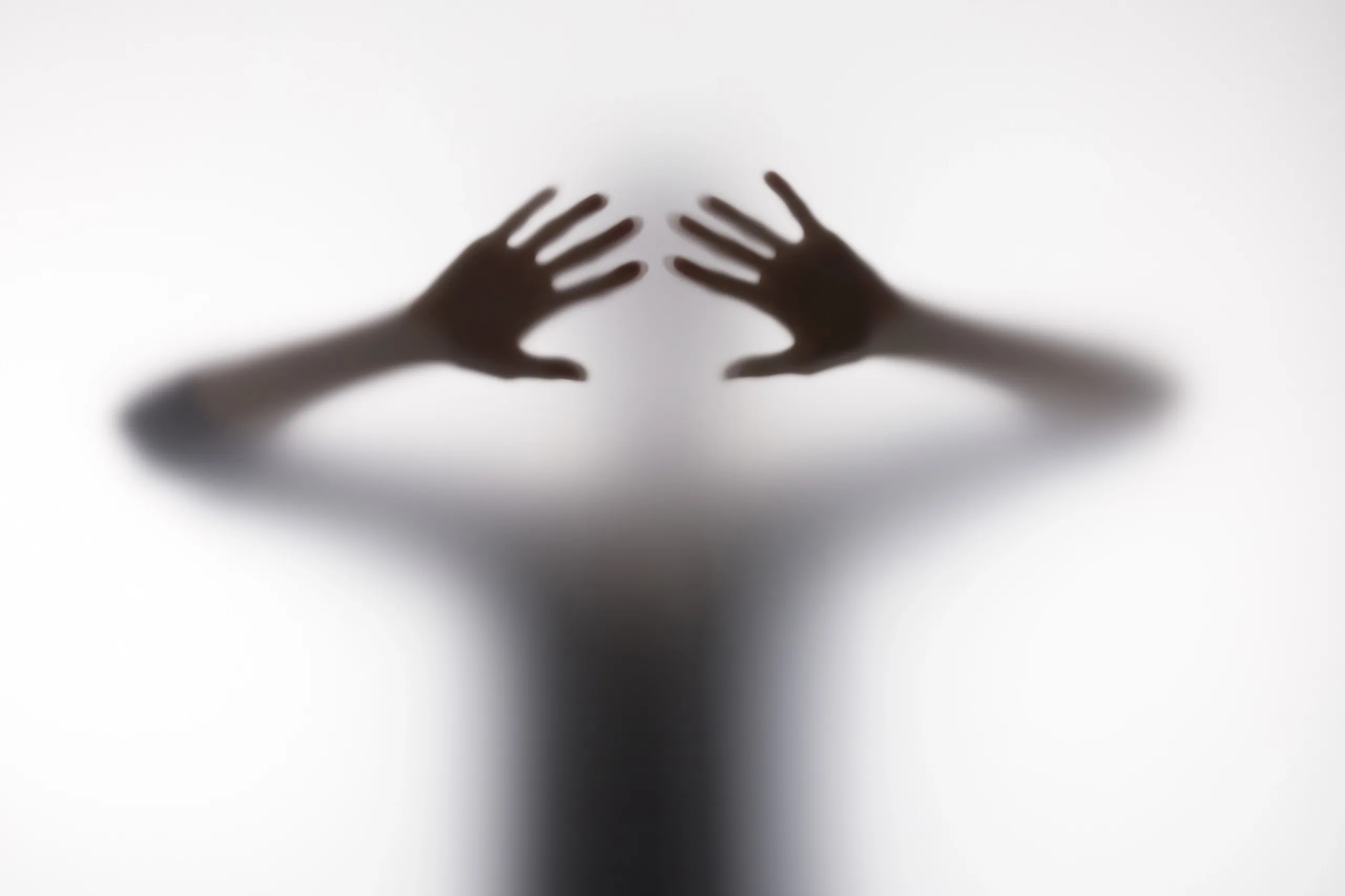 Silueta borrosa de persona detrás de un cristal que representa barreras de comunicación